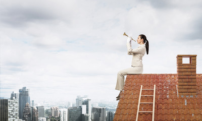 Attractive young woman playing trumpet on roof