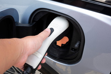 hand holding Power supply socket connect to electric vehicle for charge to the battery