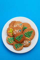 cookies with Christmas decoration on white plate on blue background