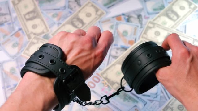 Close-up of a man putting black handcuffs on his hands.