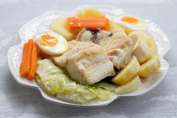 boiled fish with vegetables and boiled egg on white plate