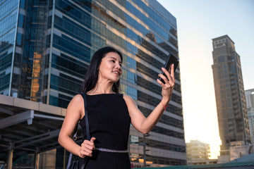 Fototapeta na wymiar Asian active woman holding a phone in a central business district