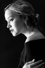 Beautiful tender blonde. Black-white portrait. Black background. Vertical.