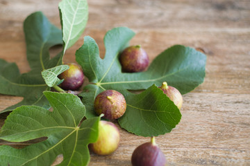 Fig fruits and fig leaves on wooden table.
