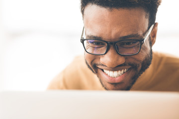 Smiling black man coder looking at laptop