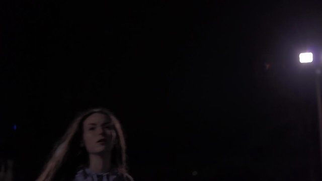 Epic slow motion shot of teenage girl shooting basketball at night outside, backlit.