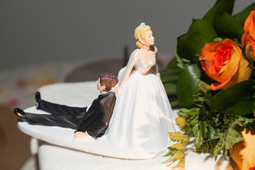 Funny figure; Bride and groom figurine in funny action on wedding cake.