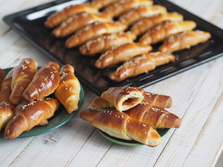 Ready-made toasted homemade bagels on a black baking sheet from the oven. Ready to eat. Sprinkled with sesame seeds. Home kitchen.