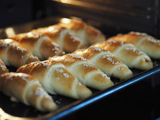 Ready-made toasted homemade bagels on a black baking sheet from the oven. Ready to eat. Sprinkled with sesame seeds. Home kitchen.