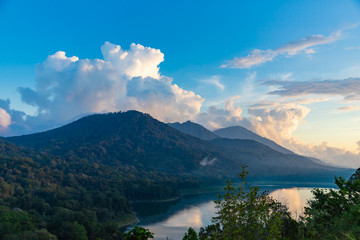 Naklejka premium Beautiful sunset over lake Tamblingan. Scenery nature landscape. Amazing view on volcanic mountains and cloudy sky. Bali island, Indonesia.