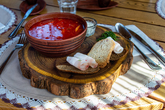 Beet soup in ceramic plate with becon, bread and sour cream on wooden board. Borch, traditional Ukrainian food