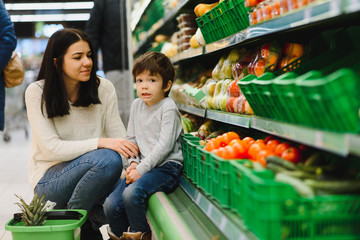 Young mother with her little baby boy at the supermarket. Healthy eating concept