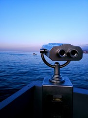 Touristic telescope stands on sea coast over blue sky background. Stationary binoculars with bill...