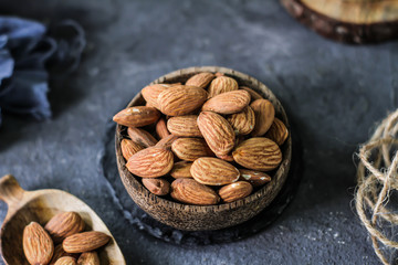 Photo of almond in a wooden bowl. Front View of almond. Almond with wooden spoon or scoop. Raw almond on the table. On rustic board. Images