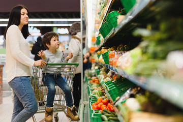 Young mother with her little baby boy at the supermarket. Healthy eating concept