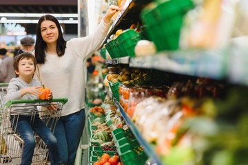 Young mother with her little baby boy at the supermarket. Healthy eating concept