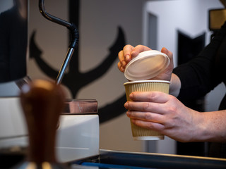 Barista covering a take-out coffee mug.