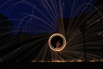 a long exposure photography of an steel wool on fire going in circles and dropping iron on fire as a shower