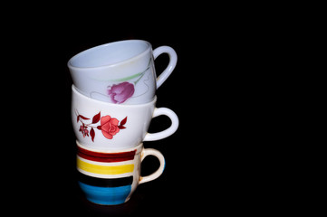 There are three cups arranged one on one on black background
