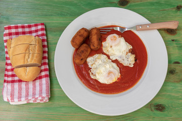 Huevos fritos y croquetas con tomate frito.