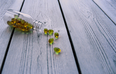 yellow pills with glass bottle on grey wooden background. Copyspace for text or advertising