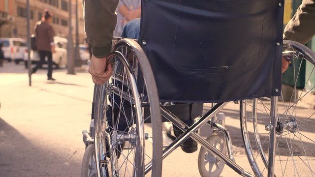 young disabled man in wheelchair on crowed sidewalk - slow motion