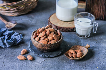 Photo of almond in wooden bowl on gray background. Almond with wooden spoon or scoop. Raw whole almond. Almond milk. Images