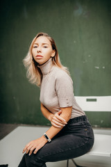 Woman sitting against dirty green background