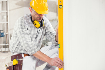 Builder using a spirit level to measure a wall