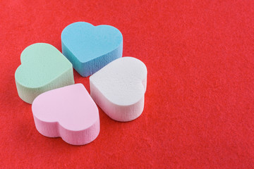 Assorted pink, blue, green and white pastel cosmetic sponges in heart shape on red felt background