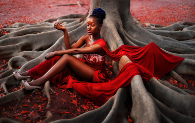 Creative photo of a young African woman in a long evening red dress.