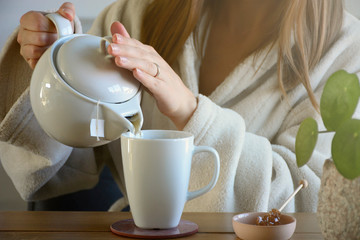 Woman in bathrobe pouring tea in the early morning