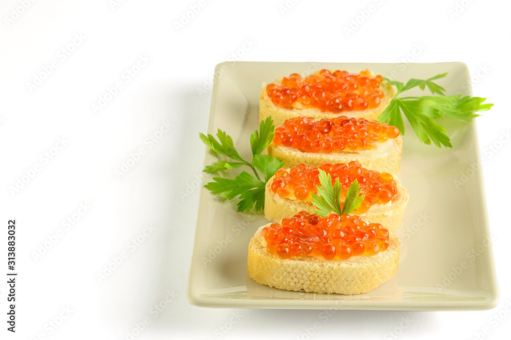 Wall mural Slices of white loaf with red caviar and parsley on the white dish and on the white background.