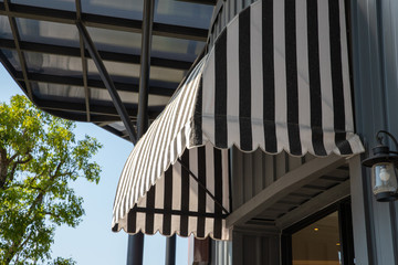 Obraz premium black and white striped awning over window frame of shop. exterior shading.