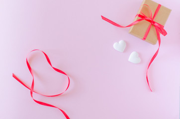 Gift box and white heart on a pink background. Valentine's day and romantic concept. Flat lay. Copy space.