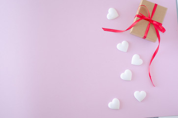 Gift box and white heart on a pink background. Valentine's day and romantic concept. Flat lay. Copy space.