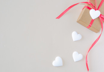 Gift box and white heart on a beige background. Valentine's day and romantic concept. Flat lay. Copy space.