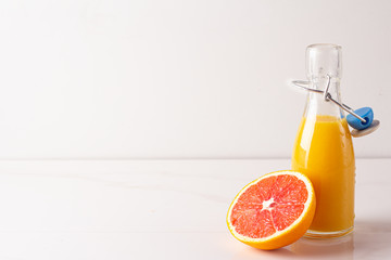 glass bottle with orange juice and red orange on a white background close-up