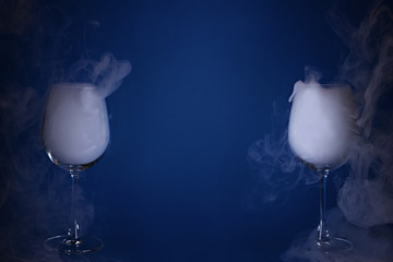 Two large wine glasses with smoke on a blue background. Color of the year 2020, Classic Blue.