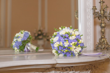 Obraz na płótnie Canvas Simply elegant bouquet of freesia and ranunculus on marble background.White and purple hydrangea blossom on white marble table, golden chandelier.Delicate bride's bouquet