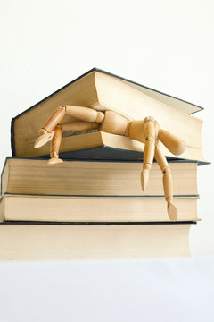 Wooden mannequin manikin student fell under pressure and was killed, crush studying and learning by bunch of books. School kills creativity. PhD studies. Difficult education and knowledge. 
