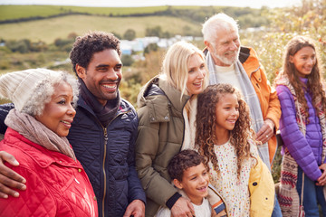 Portrait Of Active Multi-Generation Family On Winter Beach Vacation Resting By Gate