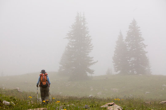 One woman hiking through the fog on her way to Twilight Peak in the Weminuche Wilderness near Silverton, Colorado