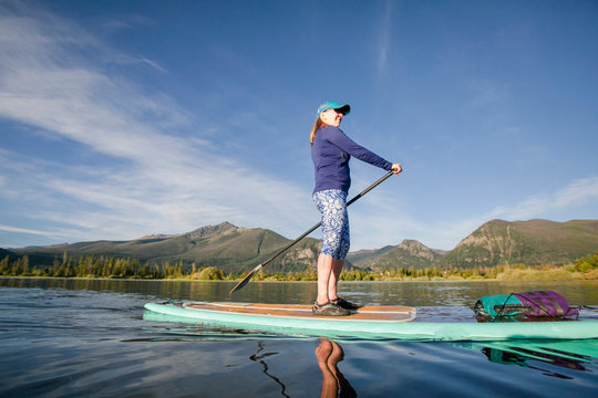One woman paddle boarding on Lake Dillon in Summit County, Colorado in the early morning.