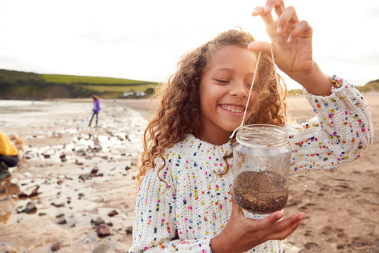 Family Looking In Rockpools On Winter Beach Vacation