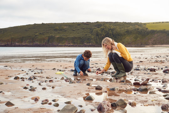 Family Looking In Rockpools On Winter Beach Vacation