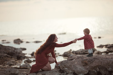 A little girl and mom walk near the sea, they play and hug