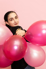 Young pretty woman in casual clothing holding festive air balloons. Portrait of happy 20s middle-eastern female celebrating valentines day, birthday, party