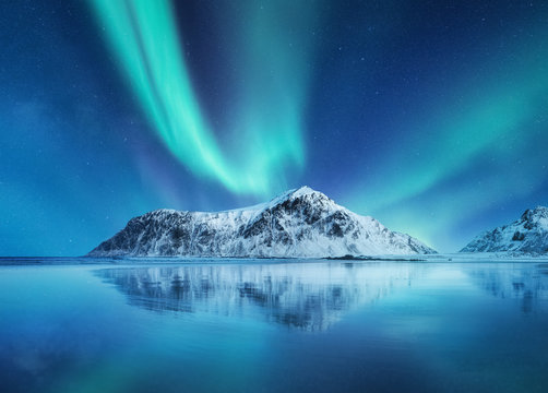 Aurora Borealis, Lofoten islands, Norway. Northen lights, mountains and reflection on the water. Winter landscape during polar lights. Norway travel - image