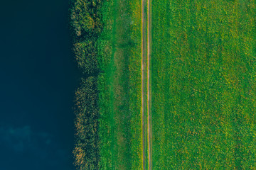 Aerial view - a country road in a green summer field near the lake. Background